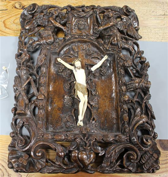 A 19th century European carved walnut and ivory crucifix, the ivory Corpus Christi on a pierced plaque decorated with angels, scrolls a